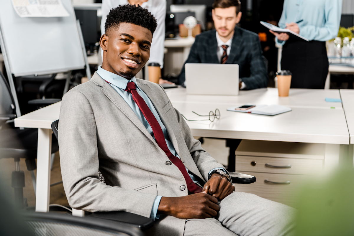 A young business professional sitting across from his colleagues in a modern office setting